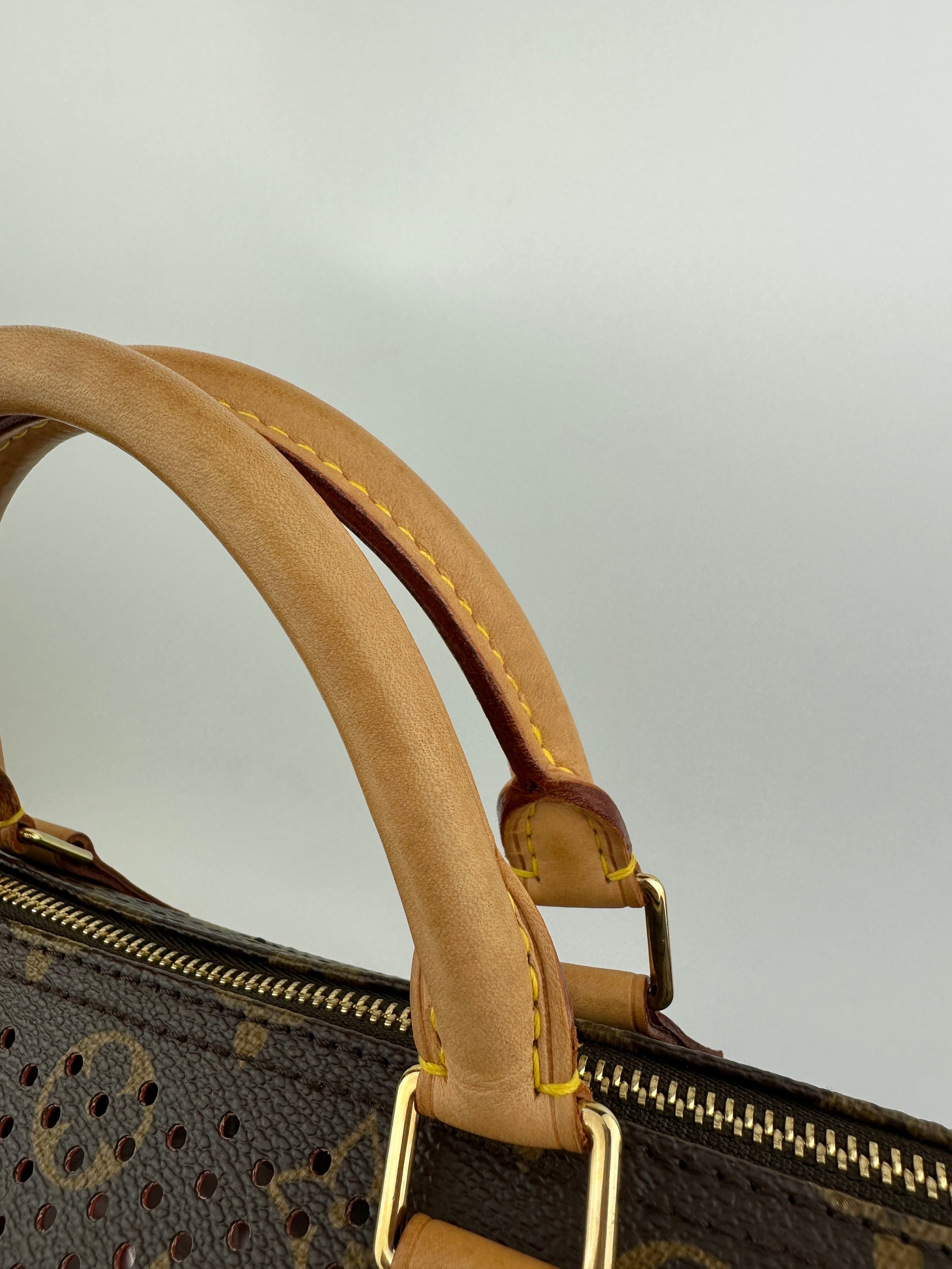 Close-up of a brown leather handle on a patterned handbag with a light gray background